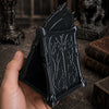 A hand holds an open black gothic skull phone stand with intricate carvings.