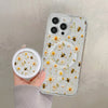 A hand holds a clear floral magnetic phone case for an iPhone featuring yellow and white flowers and bees.
