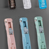 A collection of mini reusable hand clamp staplers in pink, light blue, and mint green colors.
