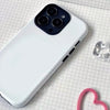 Funda de teléfono blanca con módulo de cámara negro y cable rosa sobre fondo de cuadrícula.