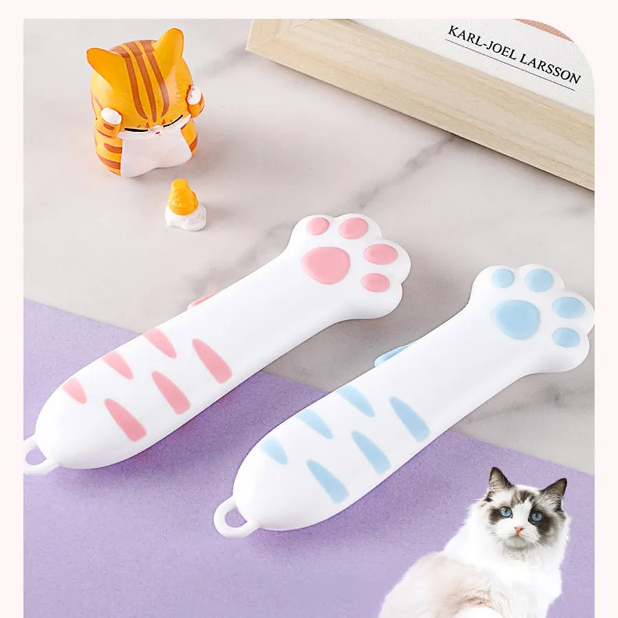 A set of cute, portable cat paw shaped utility knives and a small cat toy are displayed on a white marble surface.