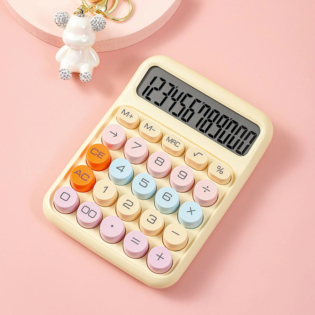 A beige mechanical 12-digit calculator with large round keys is shown on a pink background.