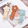 Three leather flower cable organizers in beige, brown, and mint green are displayed on a wooden surface.
