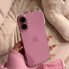 A hand holds a pink iPhone in a clear case with cat ears, resting on a light-colored surface.