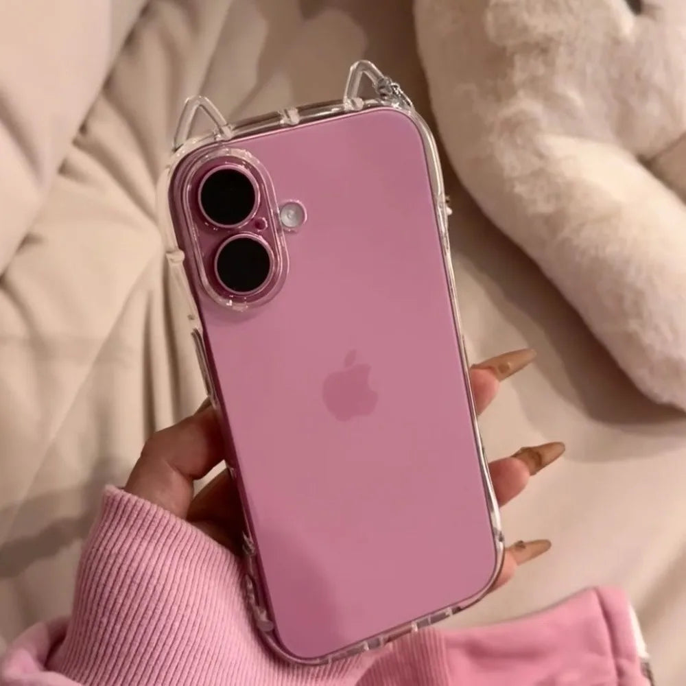 A hand holds a pink iPhone in a clear case with cat ears, resting on a light-colored surface.