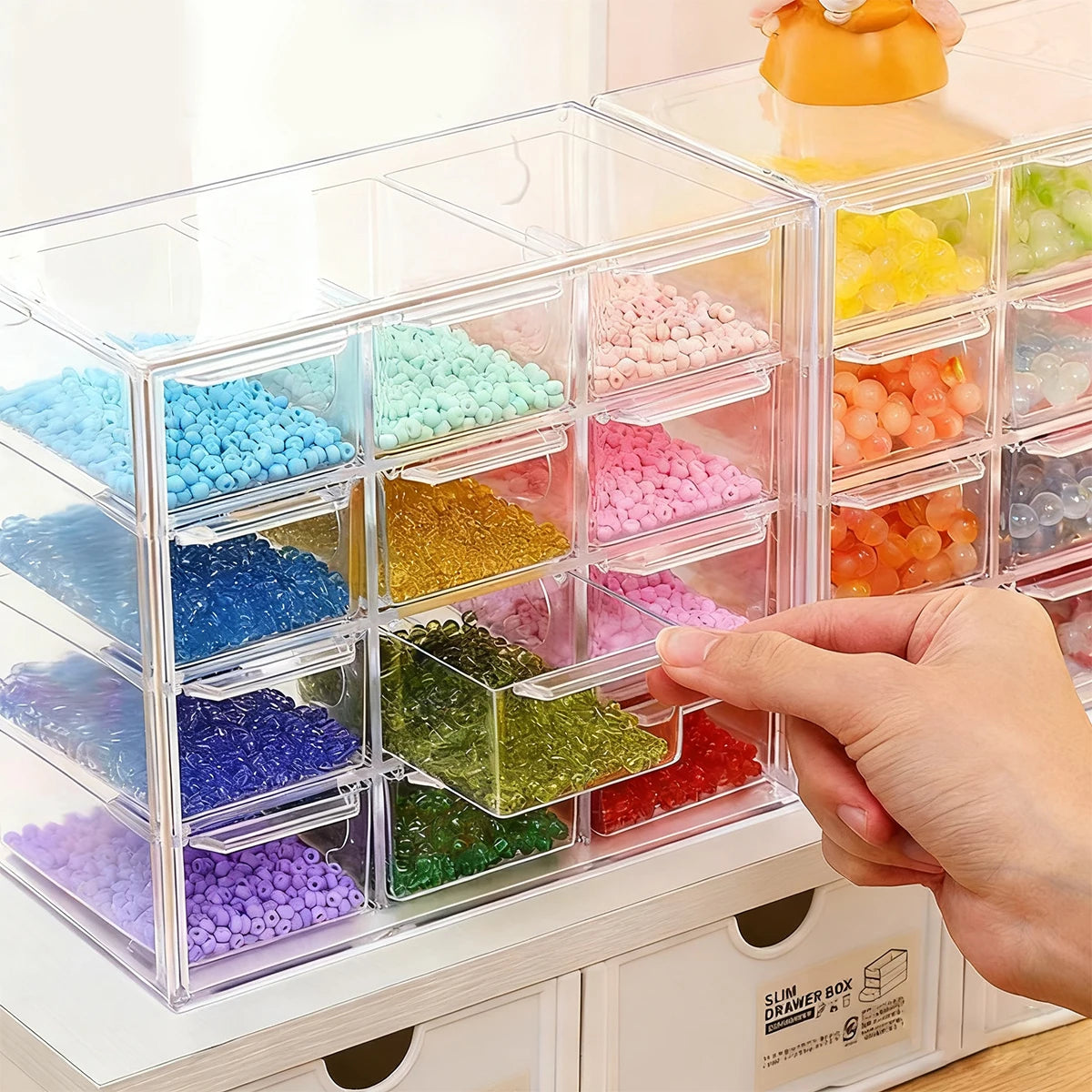Acrylic transparent bead storage box showing various colored beads in stackable compartments