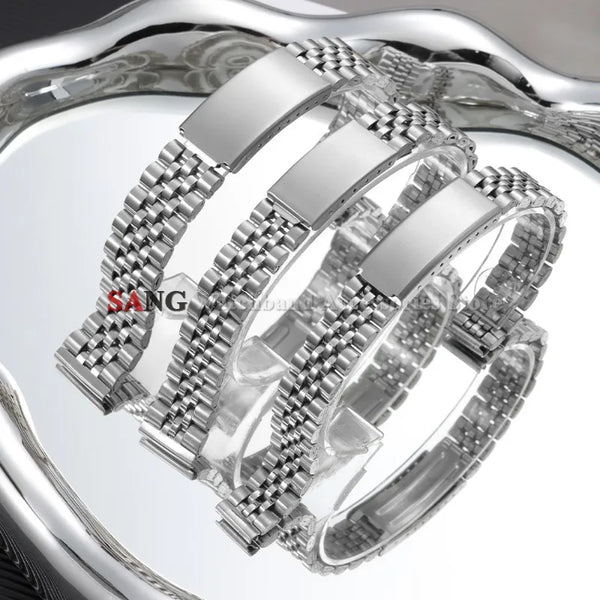 A close-up view of a polished stainless steel watch band with a folding clasp displayed on a reflective surface.