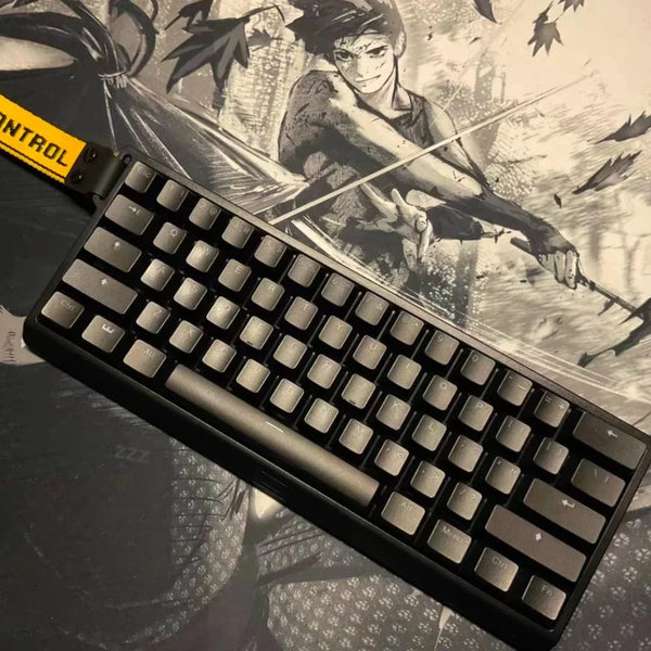 A close-up view of a black wired compact gaming keyboard with a dark illustration background.