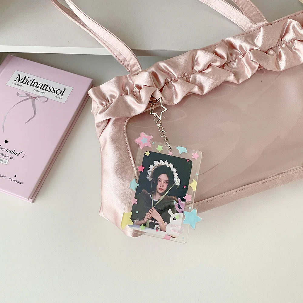 Pendentif de photocard en acrylique rose avec chaîne dorée et accents floraux, à côté d'une boîte rose.