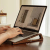Eine Person benutzt einen verstellbaren Holz-Laptopständer, um einen Laptop-Bildschirm mit einer Grafik anzuzeigen.