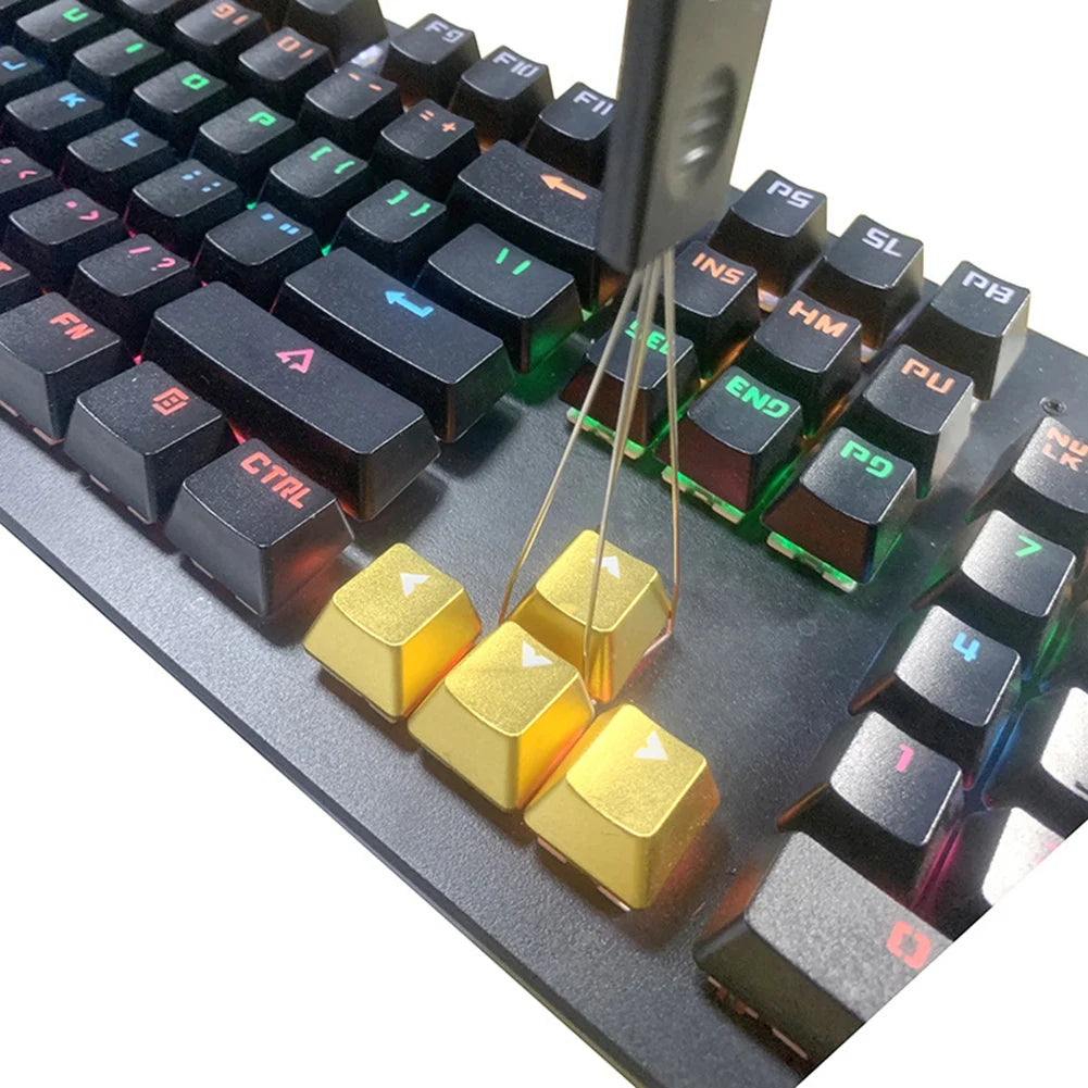A close-up view of a mechanical keyboard keycap puller tool with brass levers used for switch removal.