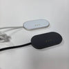 A white magnetic wireless charging adapter with a black cable lying on a white surface.