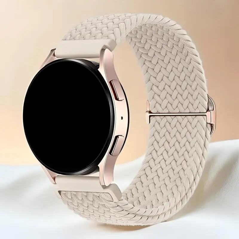 A close-up of a rose gold smartwatch with a beige woven nylon strap and a black display.