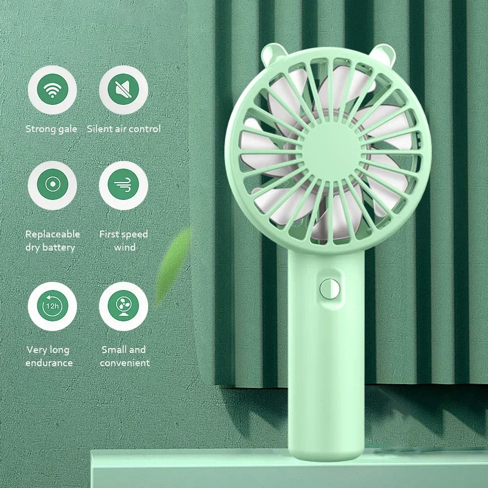 A light green mini handheld fan with a mesh grille is shown against a textured green background.