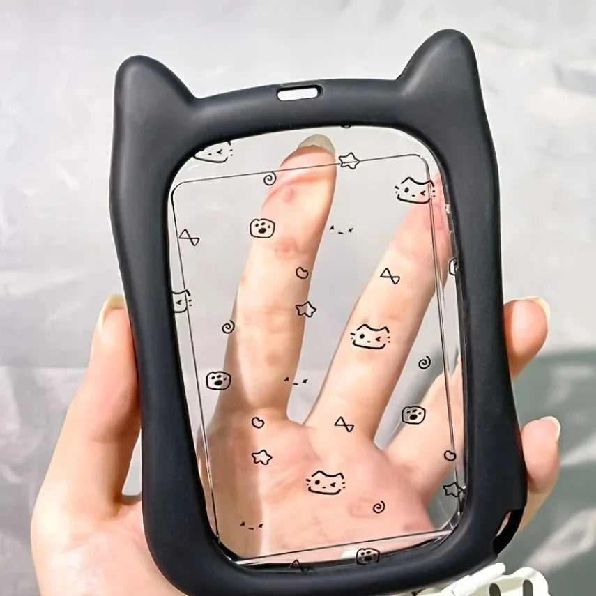 Eine Hand hält einen schwarzen Silikon-Katzen-Anhänger als Ausweishalter mit Fingerabdruckmuster auf einer klaren Oberfläche.