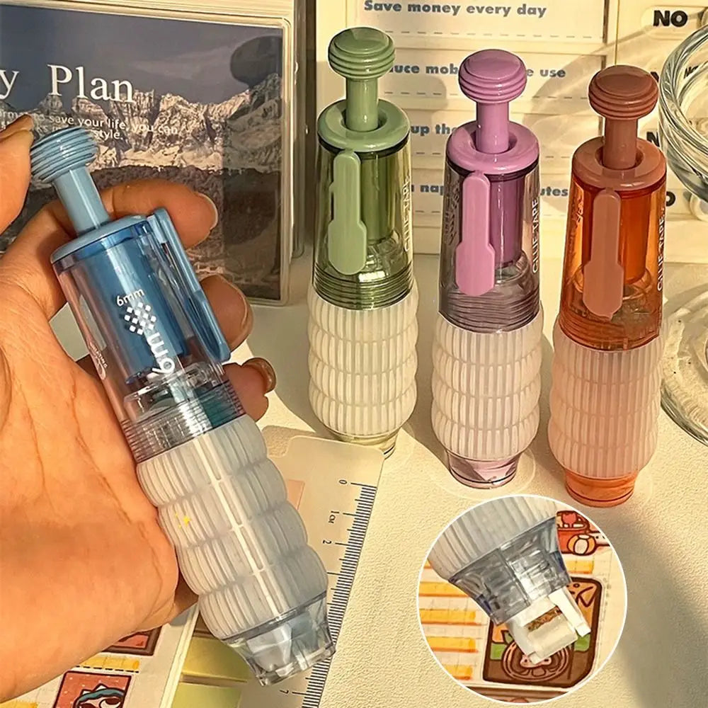 A hand holds a clear double-sided quick dry dot glue pen with a light blue cap and white body, next to several colored pens.