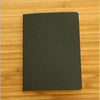 A black A6 blank sketchbook lying on a wooden surface.