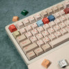 A close-up view of a white mechanical keyboard with retro AI illustrator PBT keycaps in cherry profile and dye-sublimation co