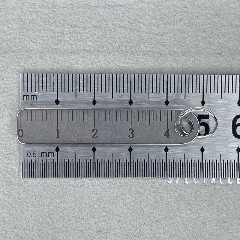 A stainless steel mini ruler keychain showing a marked scale with millimeter and half-millimeter measurements.