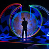 A silhouette of a person is illuminated by colorful, concentric light rings created by a magnetic RGB handheld light wand.