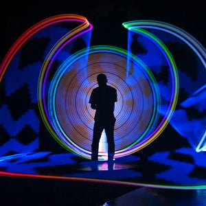 A silhouette of a person is illuminated by colorful, concentric light rings created by a magnetic RGB handheld light wand.
