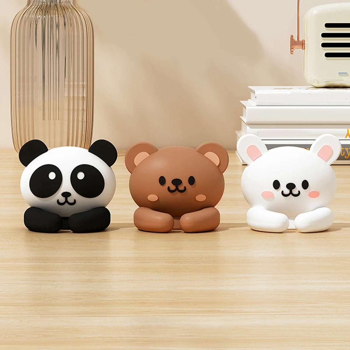 Three cartoon animal desk cable organizers in black, brown, and white sitting on a wooden surface.