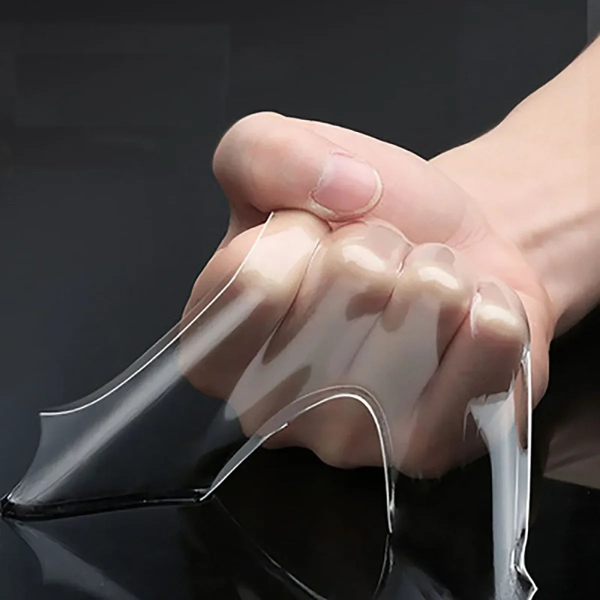 A hand is applying clear, flexible double-sided nano adhesive tape to a surface.