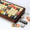 A brown tray holds various colored PBT keycaps for a mechanical keyboard, including orange, yellow, and white profiles.