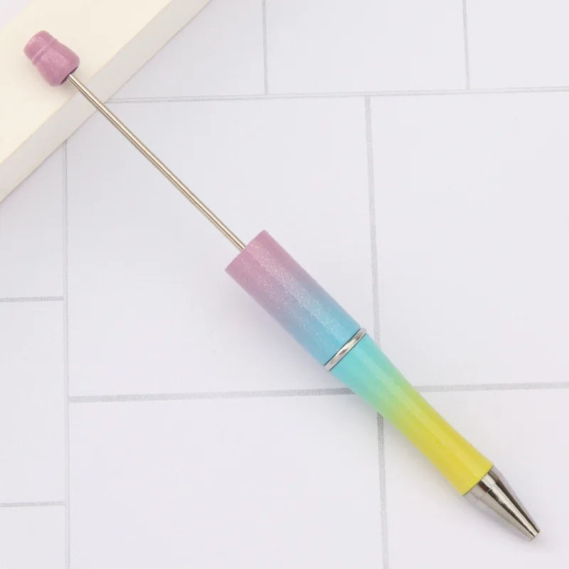 A DIY beadable pen set with a purple and iridescent gradient body and silver tip resting on a white surface.