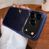 A hand holds a dark blue clear shockproof case for an iPhone, showcasing the camera lens protection features.