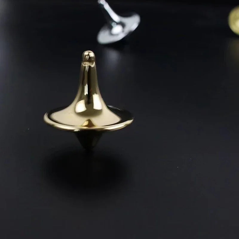 A gold-colored metal hand spinning top fidget toy resting on a dark surface.