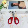 A pair of red rhinestone crafting scissors resting on a white surface next to a box.