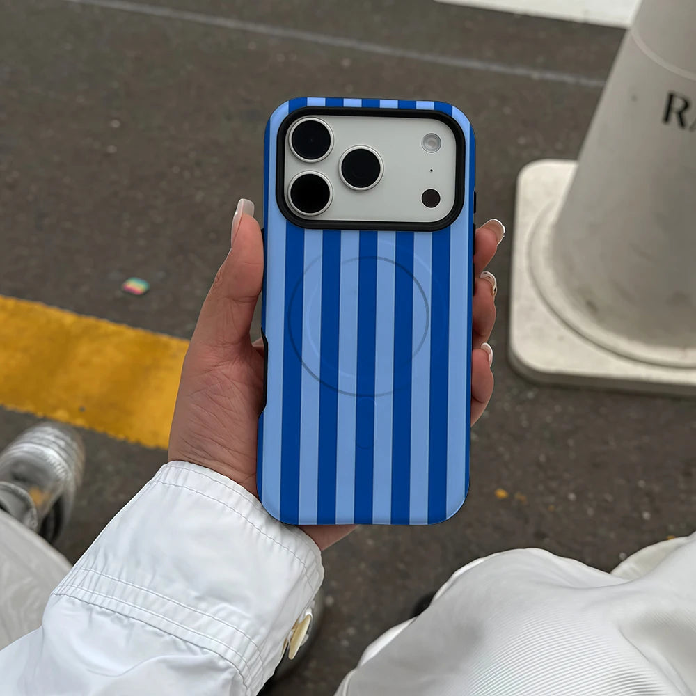 A hand holds a blue and white striped phone case for an iPhone outdoors.