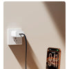 A smartphone is charging using an innovative vertical charging cable with an integrated stand on a wooden surface.