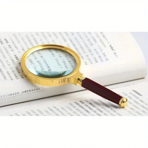 A gold-rimmed magnifying glass with a dark wooden handle is placed on a page of text.