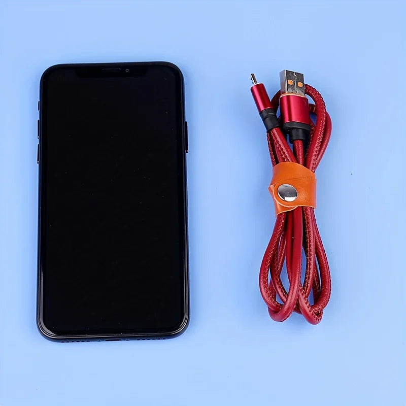 A black smartphone next to a bundle of red and black faux leather data cables and earphones.