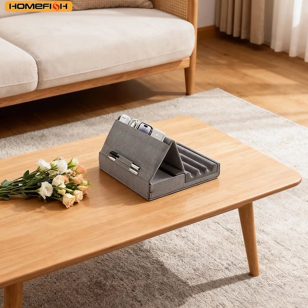 A gray foldable tablet pillow stand with a pocket resting on a wooden table next to a floral arrangement.