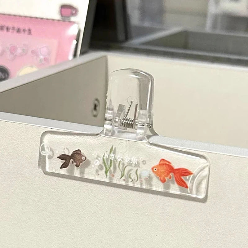 Frosted transparent book page clips featuring small fish and plant designs