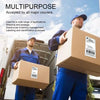 A man in blue overalls is holding a cardboard box with a shipping label, standing next to a truck.