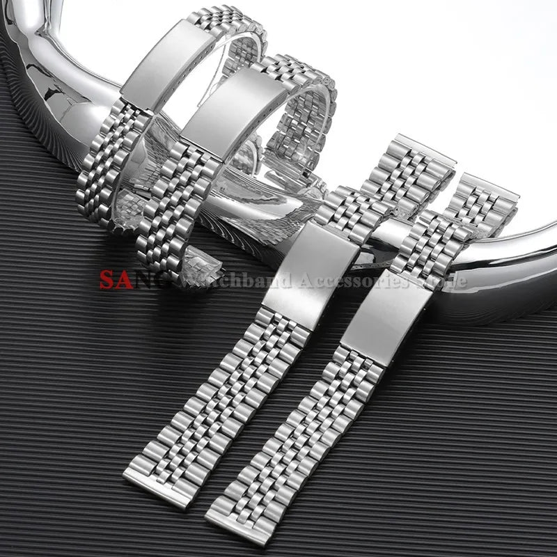 A close-up of a polished stainless steel watch band with a folding clasp resting on a dark surface.
