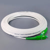 A coil of white single-mode fiber optic cable with a green connector attached.