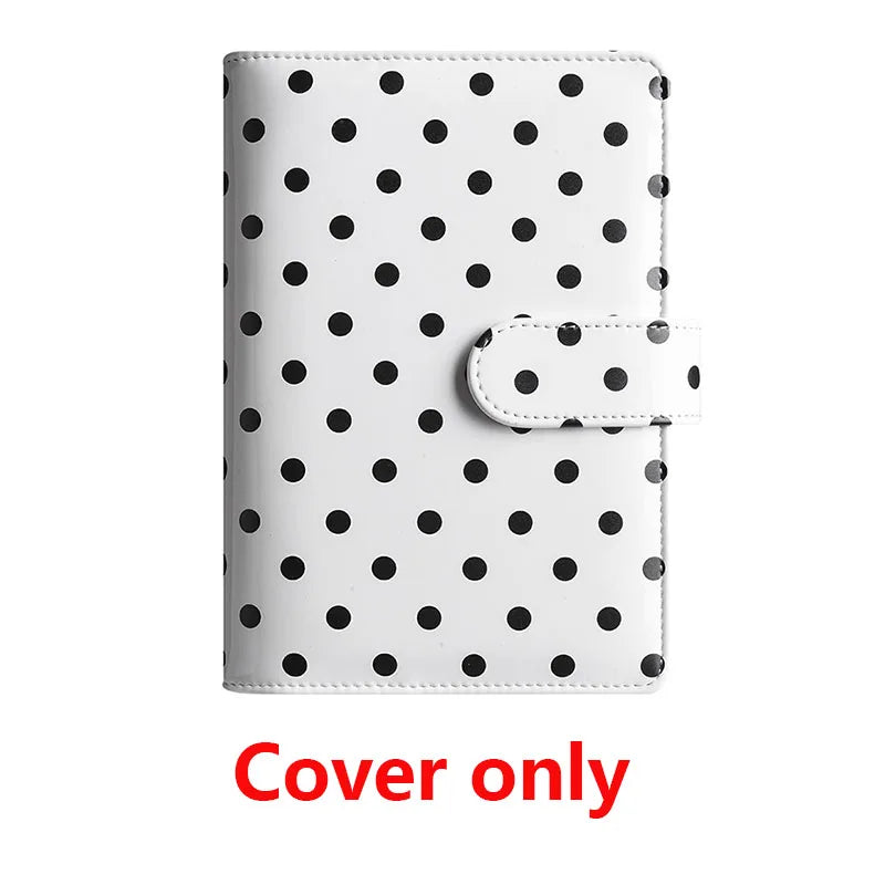 White leather binder cover with black polka dots and a clear elastic closure.