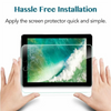 Hands applying a clear tempered glass screen protector to an iPad screen.