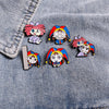 A set of five colorful cartoon anime brooches pinned on a denim fabric.