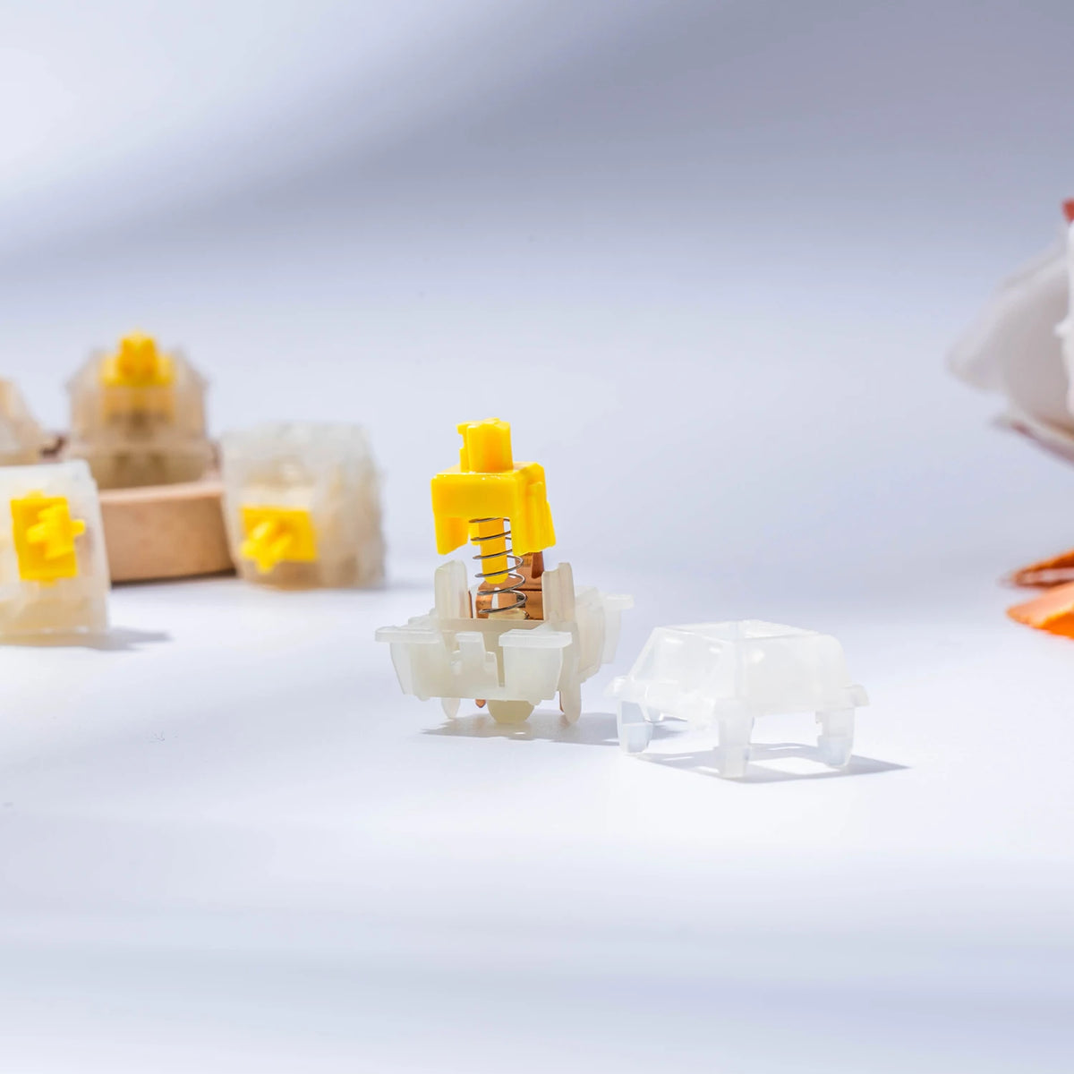 A close-up view of various milky yellow hot-swap mechanical keyboard switches and components.