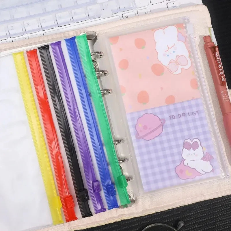 A clear PVC zipper binder with multiple colored pockets for storing cash and small items.