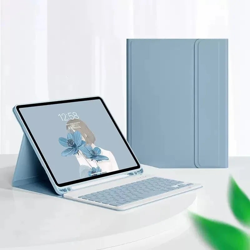 حاسوب محمول فضي أمام علبة جلدية زرقاء فاتحة لجهاز آيباد مع لوحة مفاتيح بلوتوث.