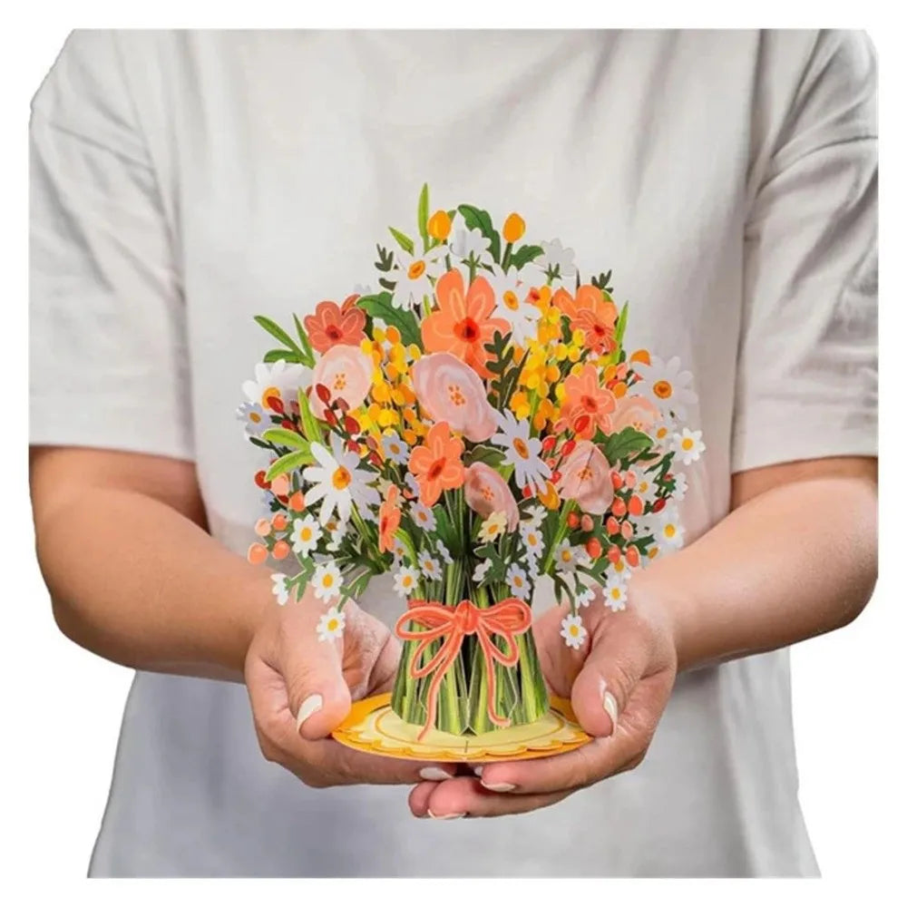 A hand holds a vibrant bouquet of orange, yellow, and white cherry blossoms and greenery.