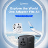 A black universal travel adapter with multiple USB ports is shown against a light blue sky and clouds.