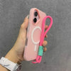 A hand holds a pink phone case with a white circular design and a pink lanyard attached to it.